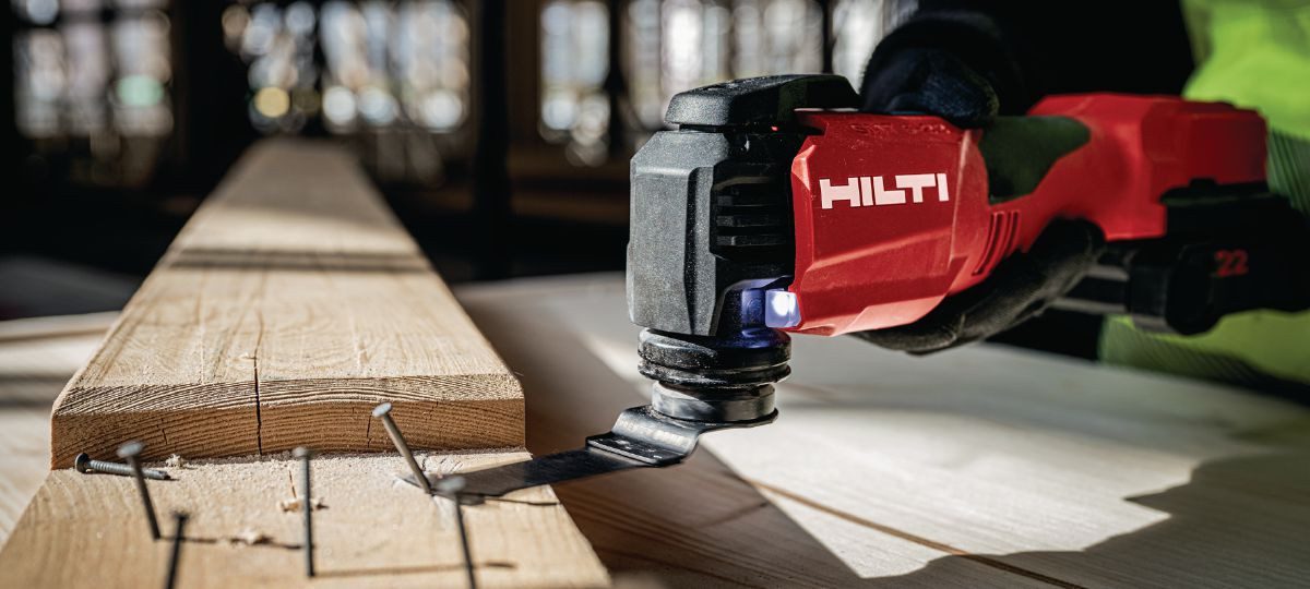 The Hilti multi-tool is used to remove bent nails from a wooden beam.
