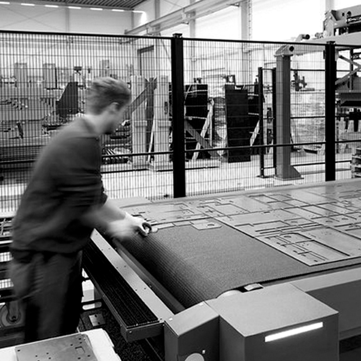 Arbeiter sortiert gelaserte Blechteile vom Förderband der Remmert GmbH ab